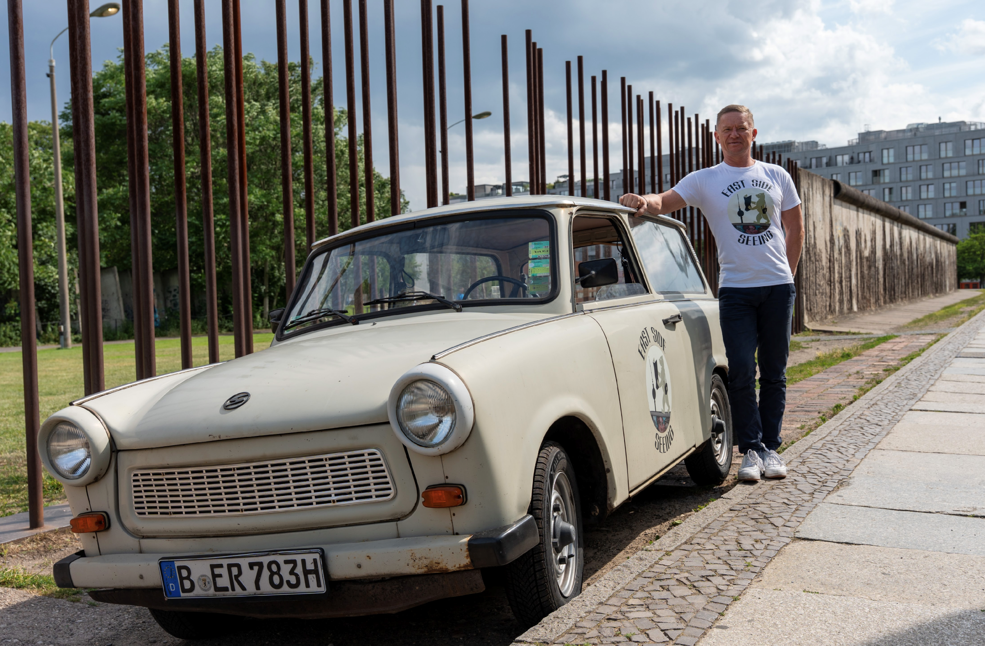 Originaler DDR-Trabant Baujahr 1983 vor der Gedenkstätte Bernauer Straße, eingebettet in die historische Kulisse der Berliner Mauer, die die bewegende Geschichte von Flucht und Unfreiheit erzählt.