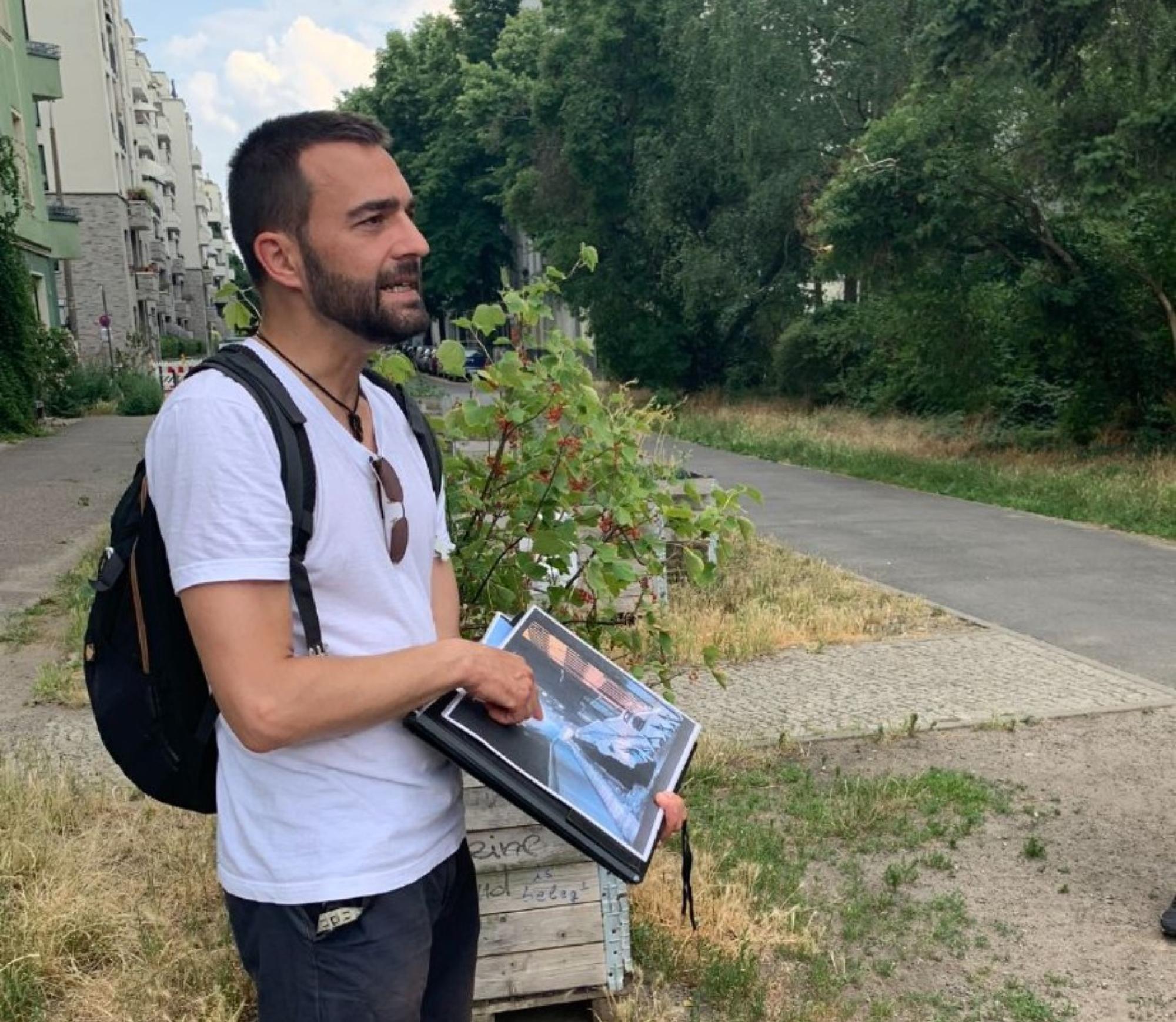 Ein Tourguide zeigt Besucher:innen etwas auf einem Bild.