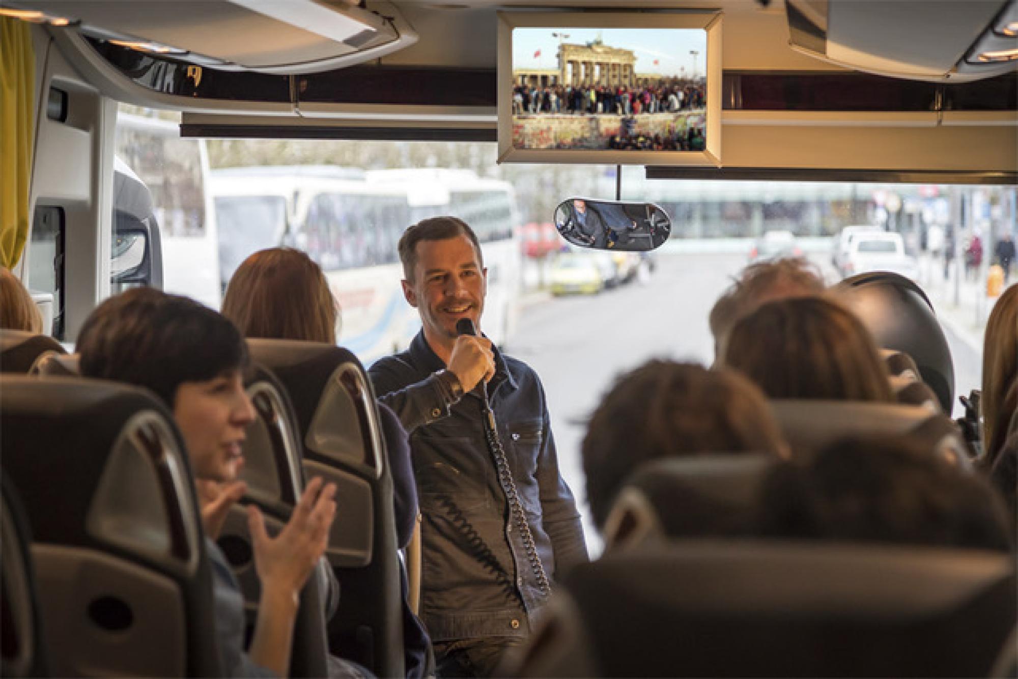 Ein Mann spricht während einer Bustour in ein Mikrofon.