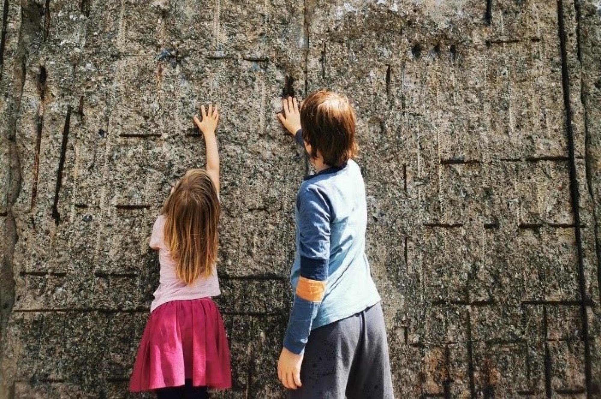Zwei Kinder stehen vor der ehemaligen Berliner Mauer