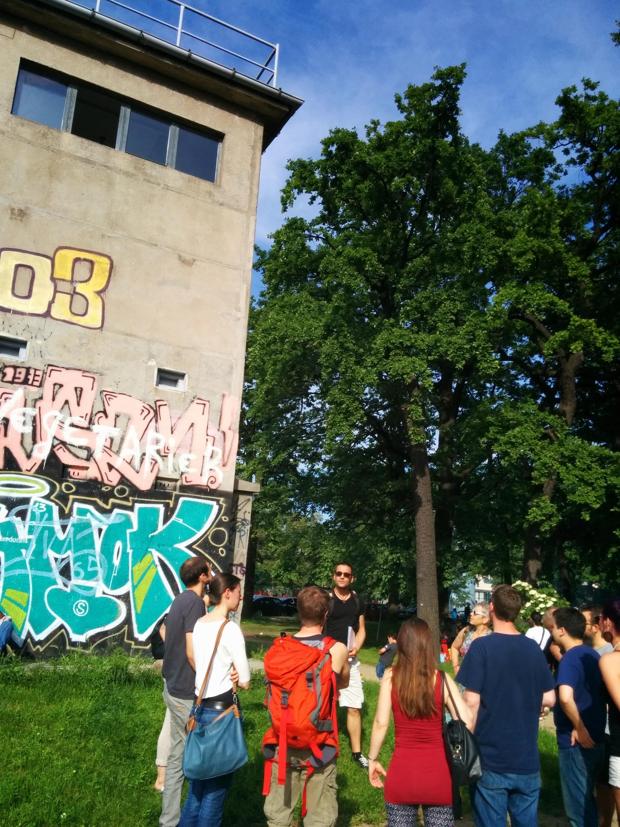 Menschen stehen vor einem ehemaligen Wachturm.