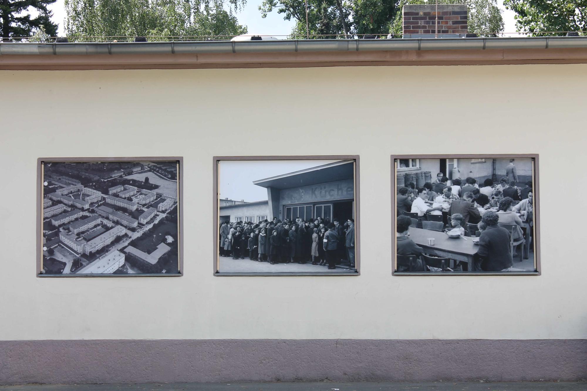 Eien Außenwand des Notaufnahmelagers Marienfelde mit historischen Fotos von Flucht.