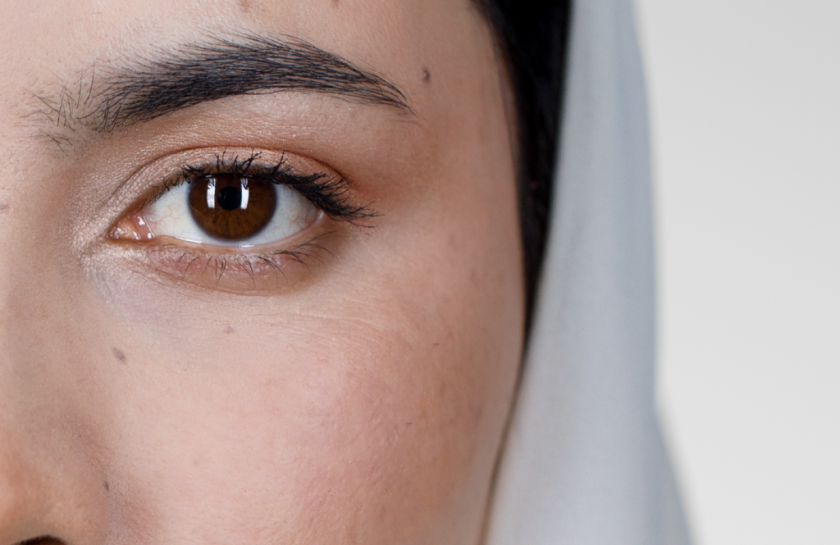 Das Auge einer Frau mit Hijab. Das weiße Kopftuch ist im Hintergrund zu sehen.