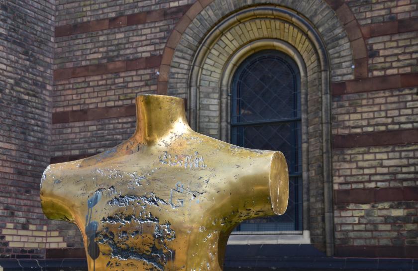 Eine goldene Stature vor der Wand einer Kirche.