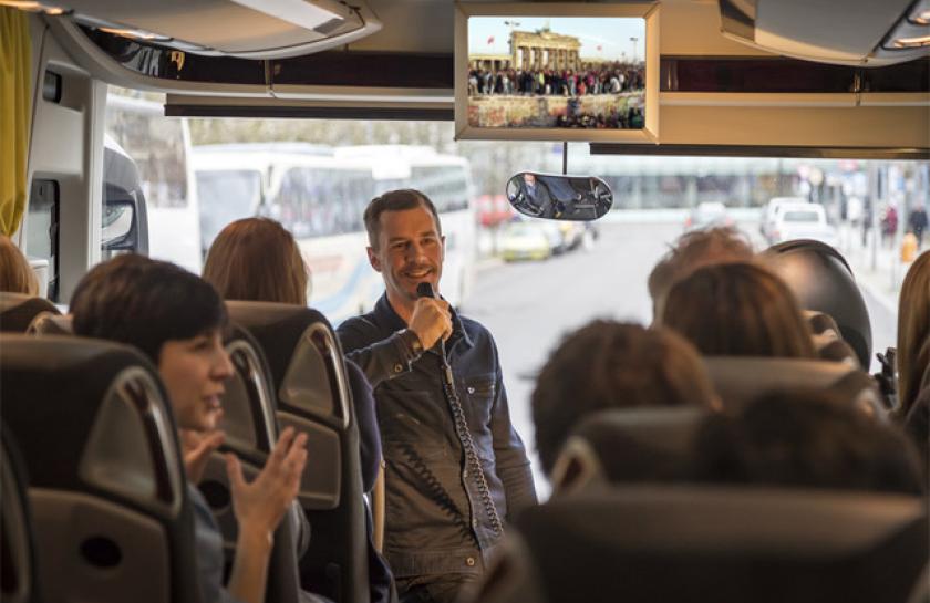 Ein Mann spricht während einer Bustour in ein Mikrofon.