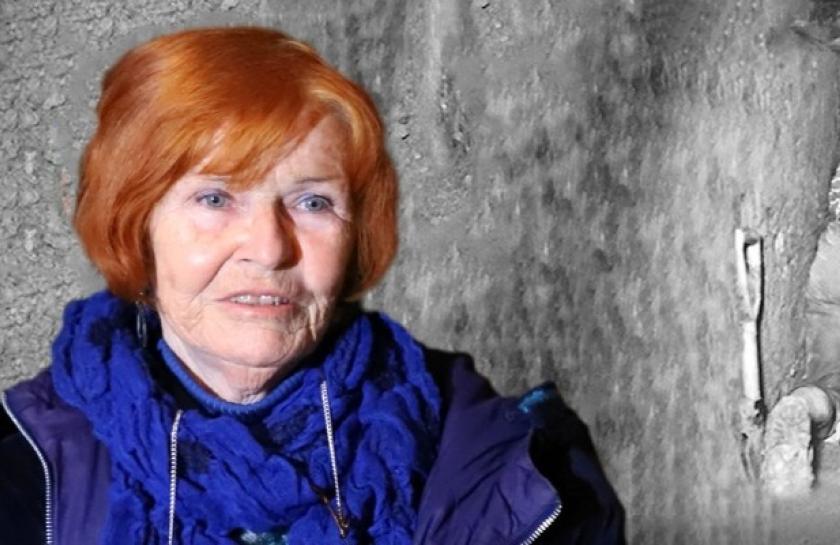 Ein Bild von Eveline Rudolph, einer Frau mit roten Haaren, vor einem Fluchttunnel in schwarzweiß.